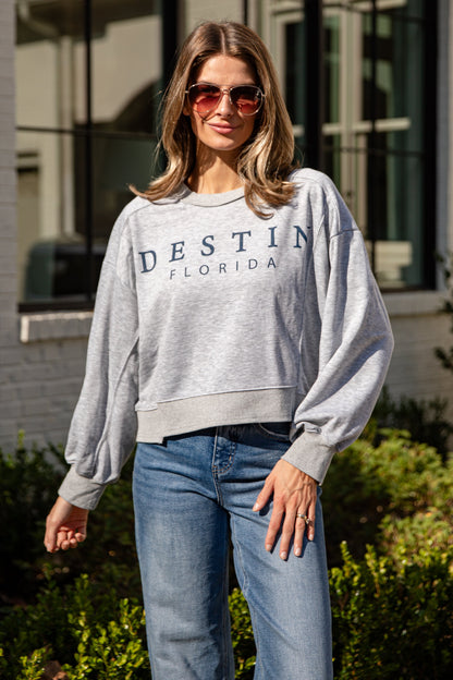 Woman wearing a gray sweatshirt with &