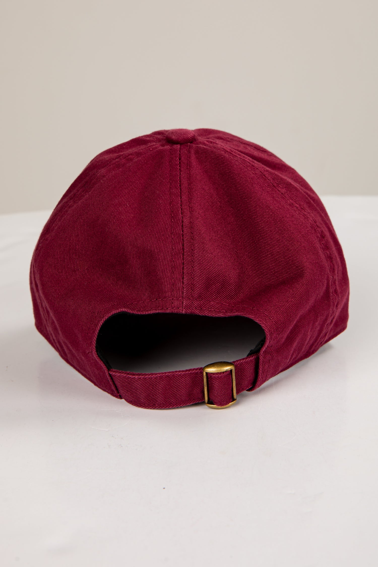 Maroon cap with a gold buckle on a white background