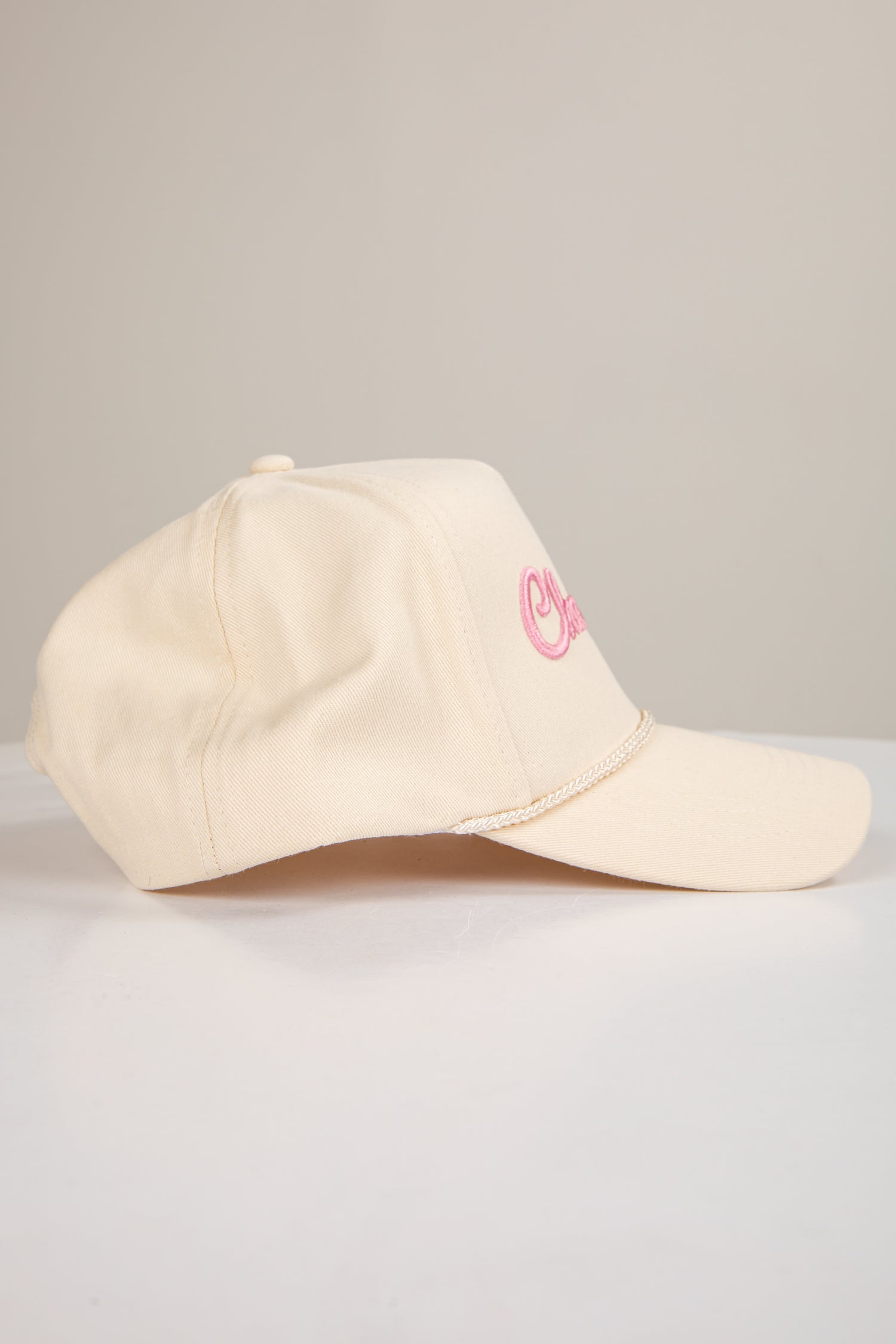 Beige cap with pink logo on a light gray background