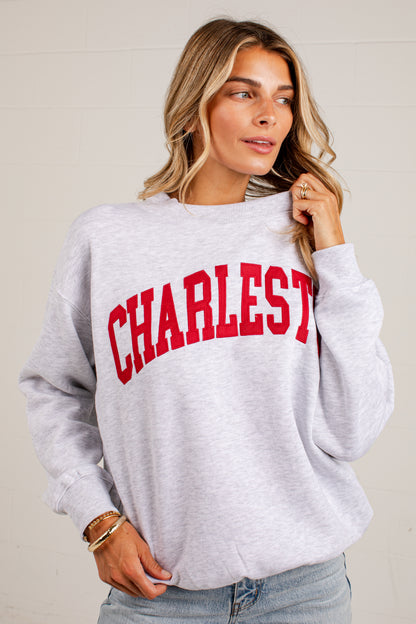 A woman wearing a light heather gray sweatshirt with &