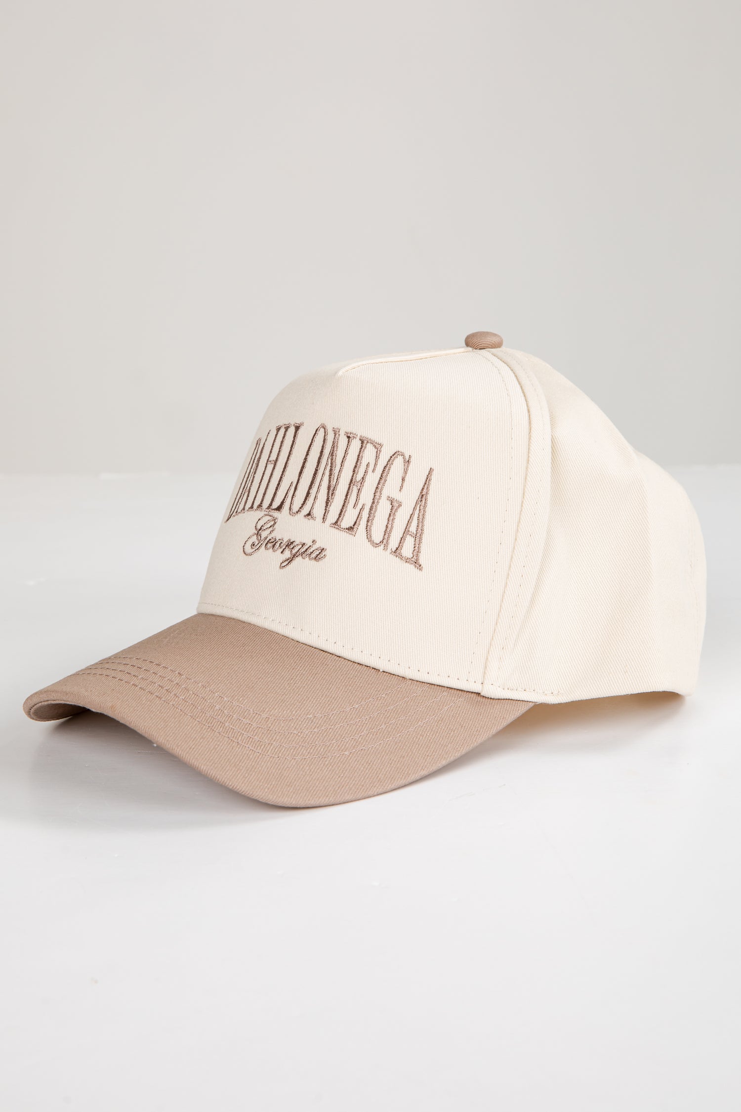 Two-tone beige and brown cap with text on a light gray background