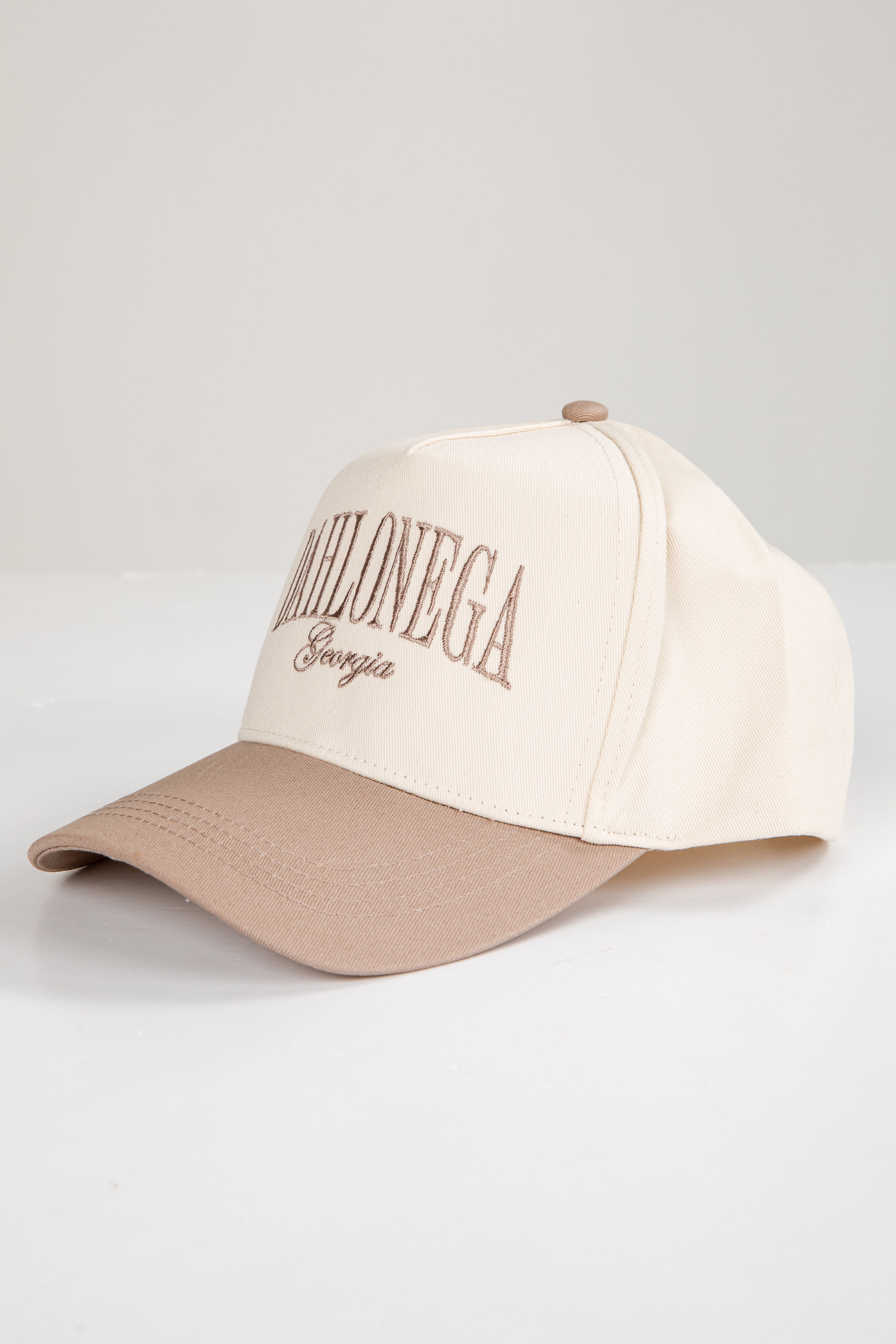 Two-tone beige and brown cap with text on a light gray background