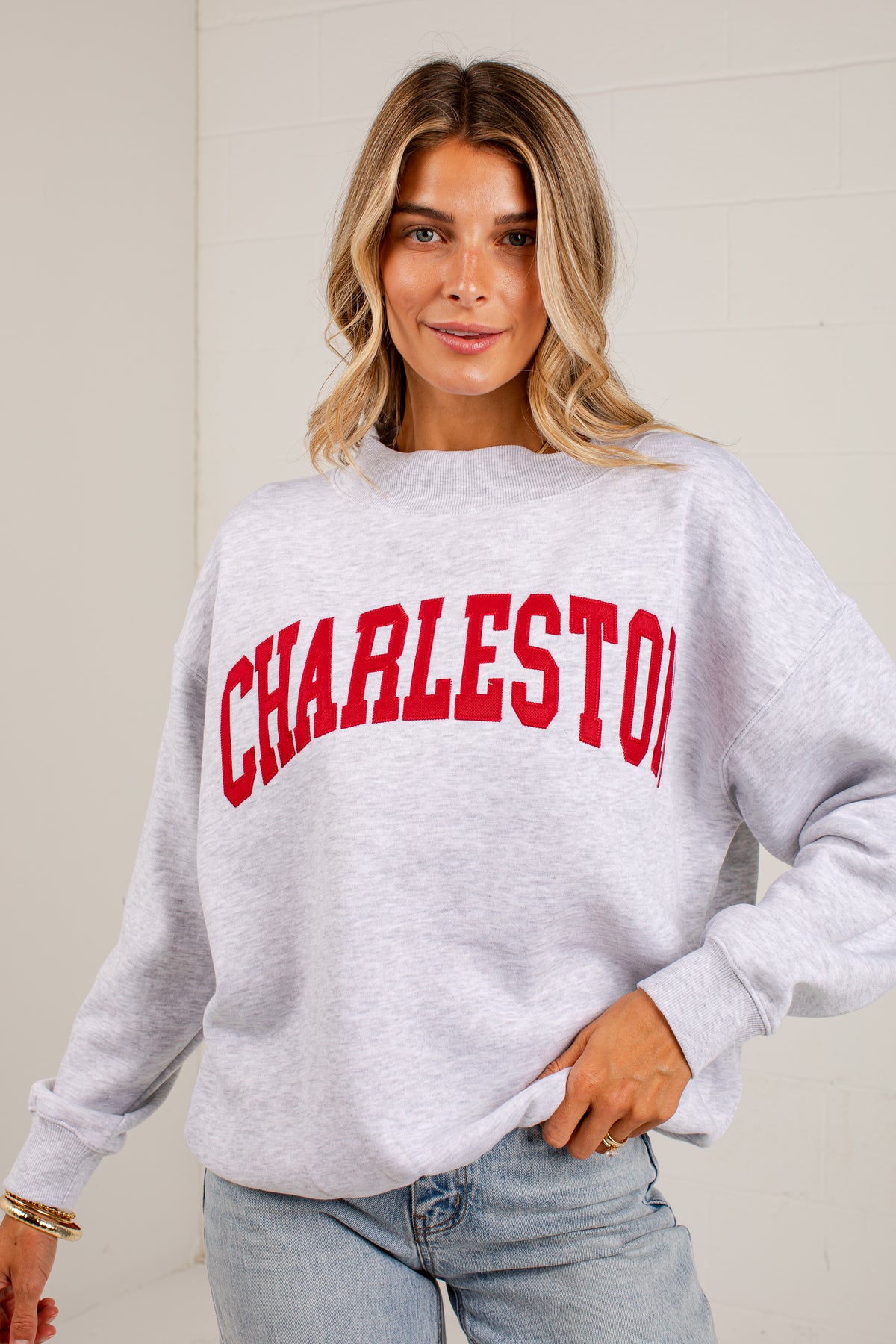 A woman wearing a light heather gray sweatshirt with &