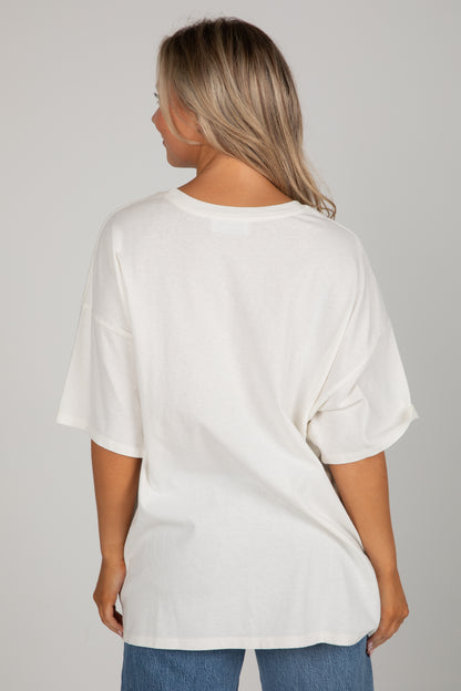 Person wearing a white oversized t-shirt and blue jeans on a gray background
