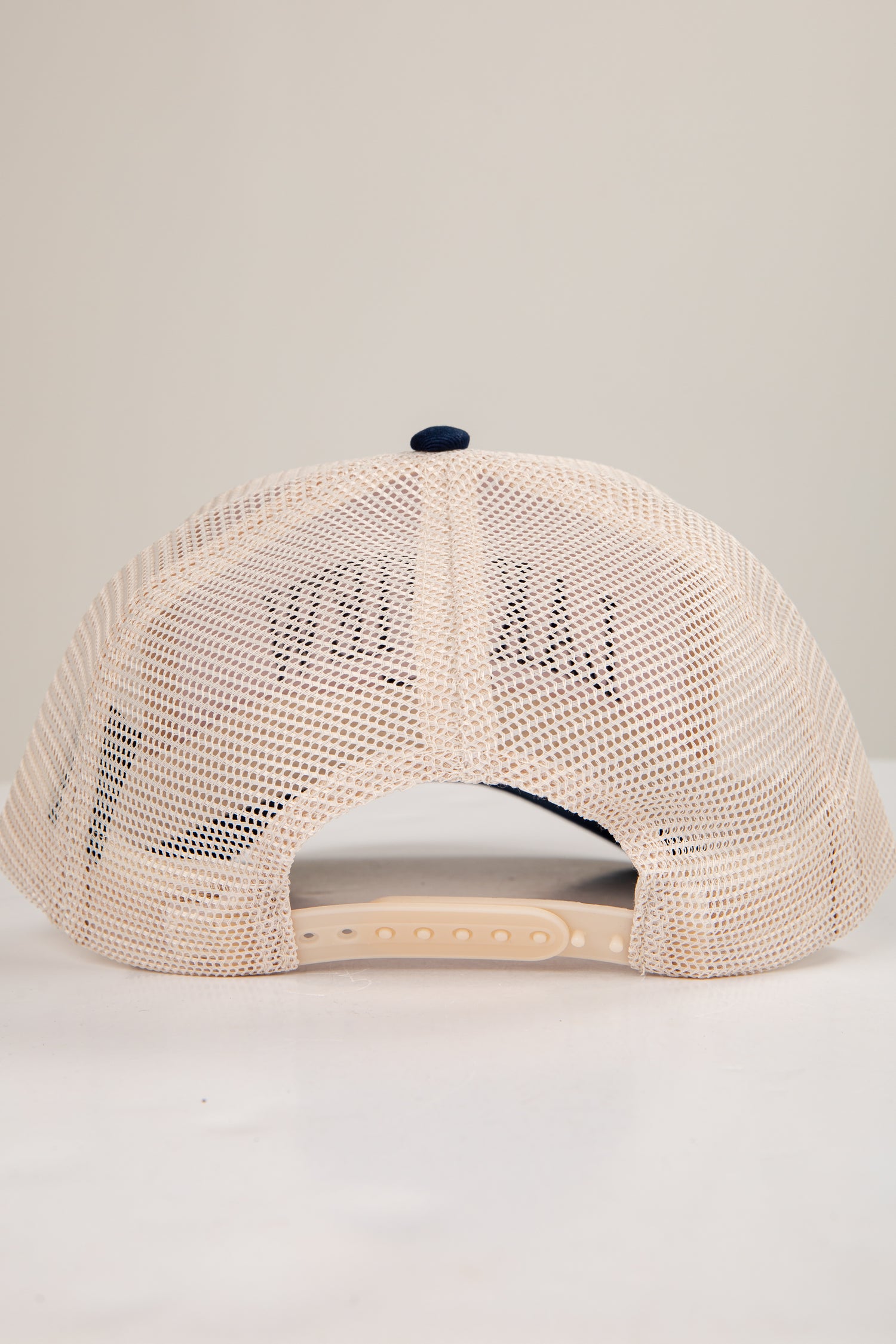 Beige mesh cap with a small logo on a light gray background