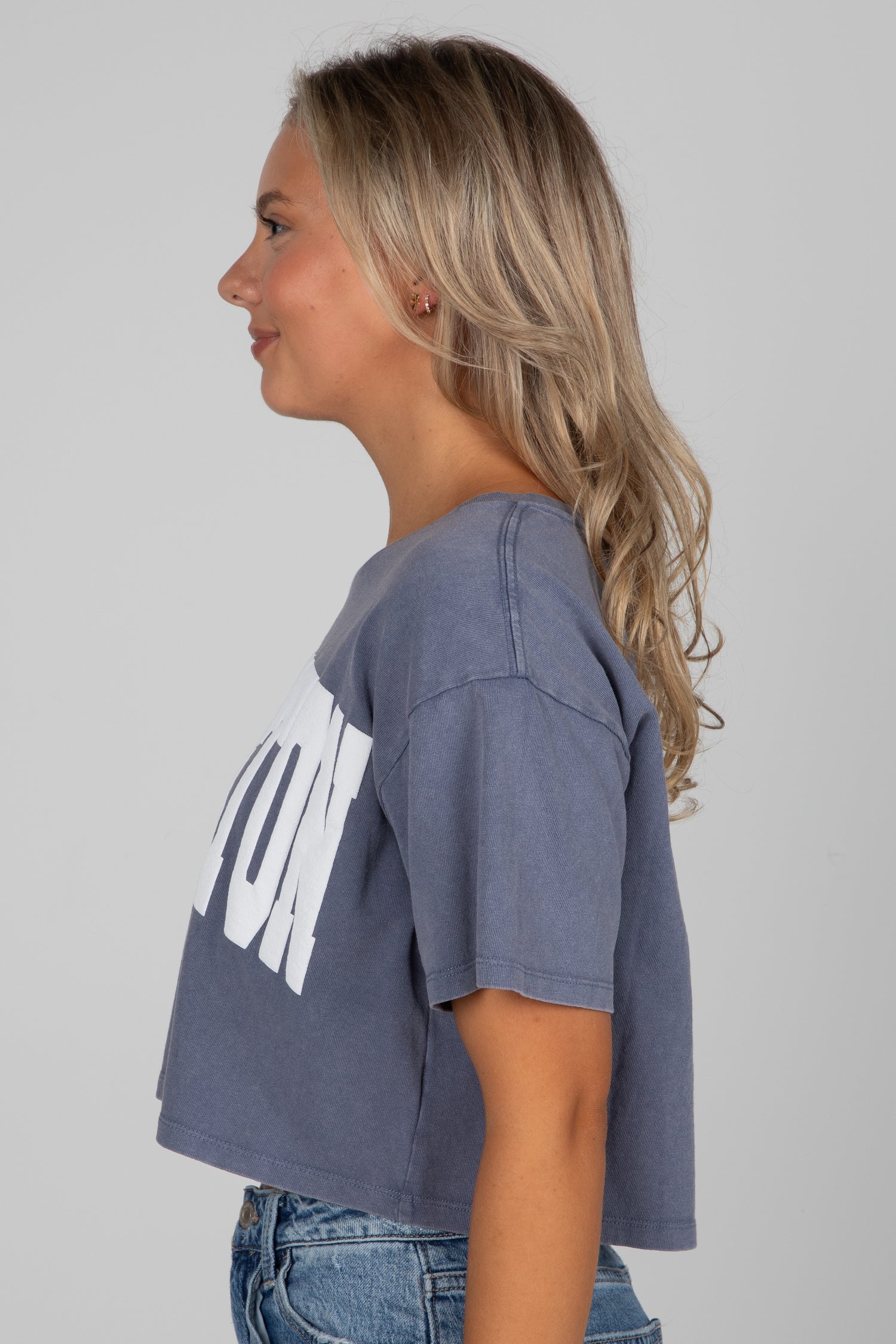 Woman wearing a blue t-shirt with a white graphic design on a plain background