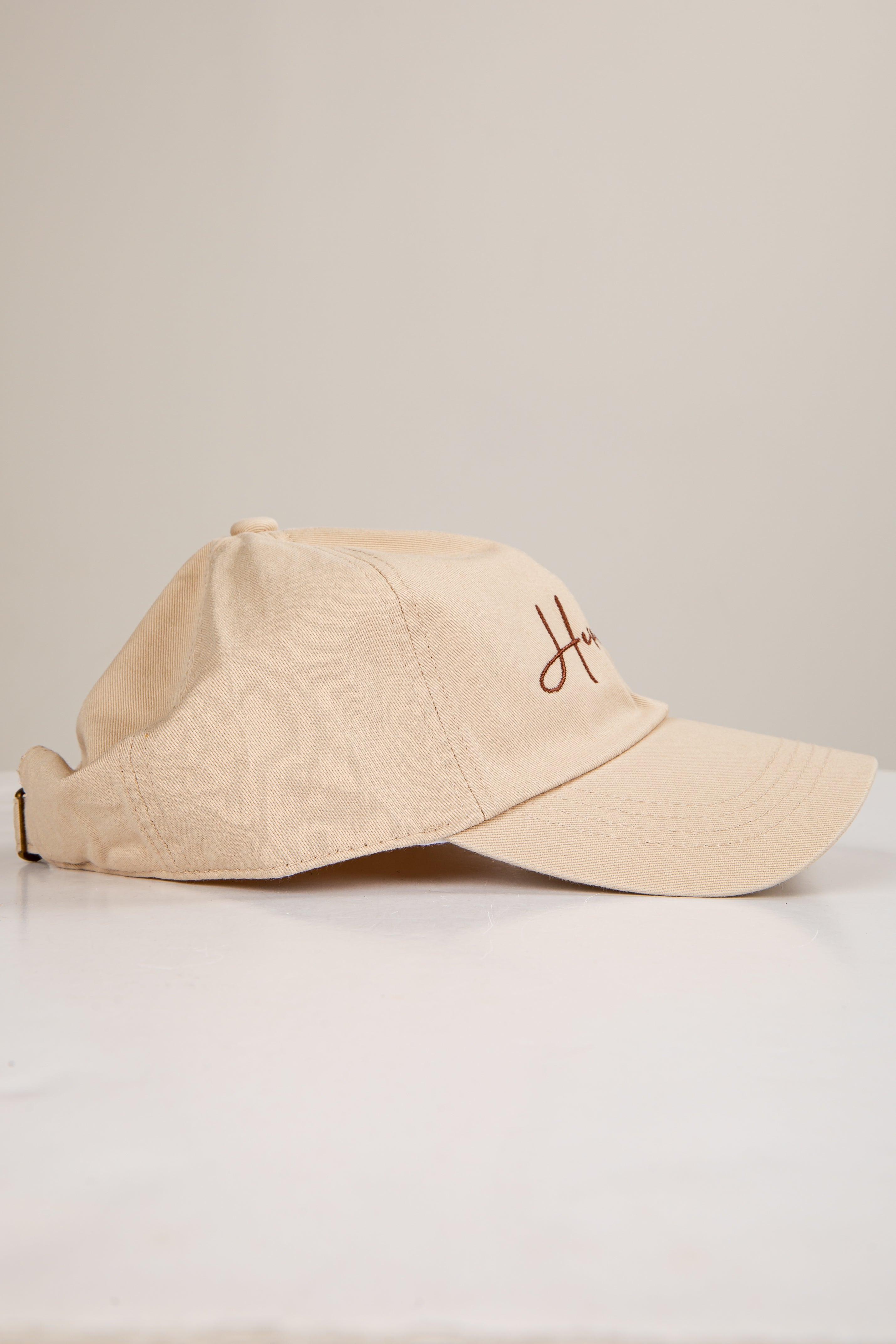 Beige cap with a logo on a light gray background
