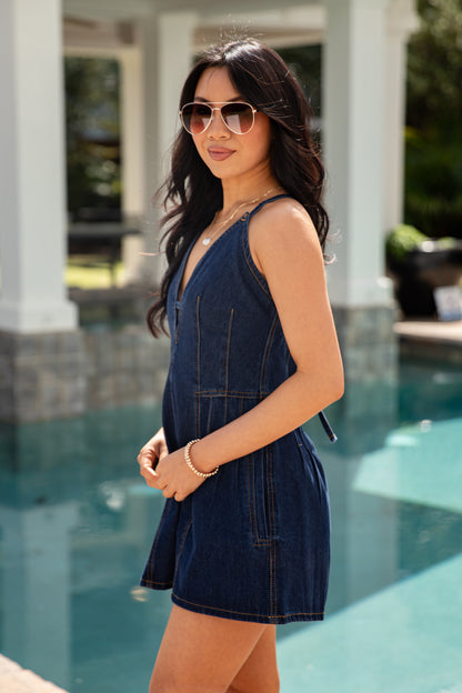 Woman in a denim dress standing by a pool