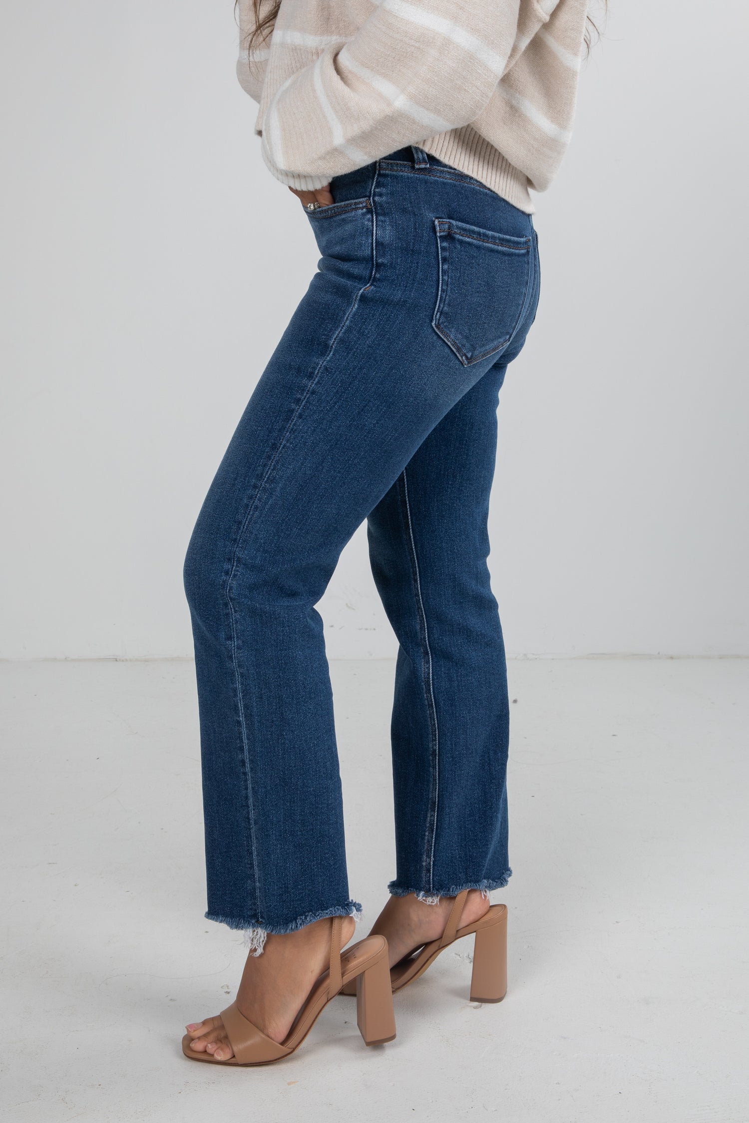 Person wearing blue jeans and a beige sweater on a white background