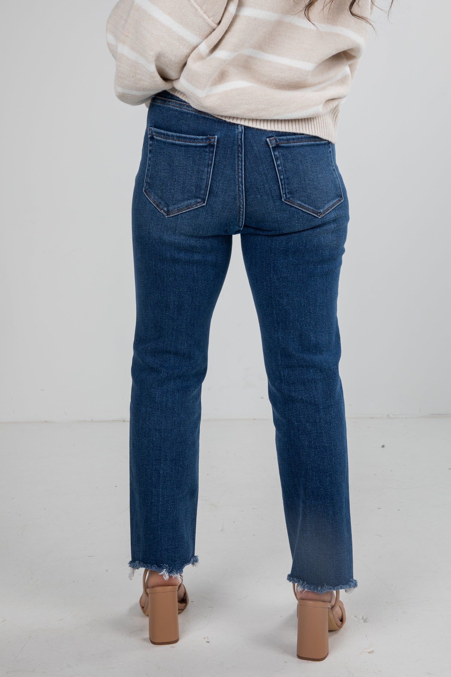 Person wearing blue jeans and a beige sweater on a white background