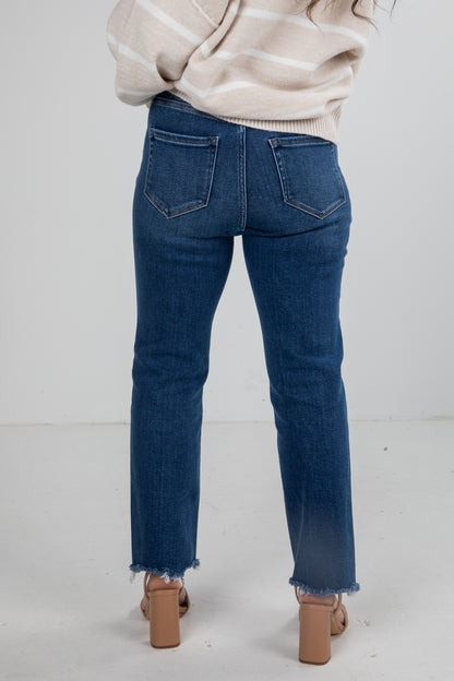 Person wearing blue jeans and a beige sweater on a white background