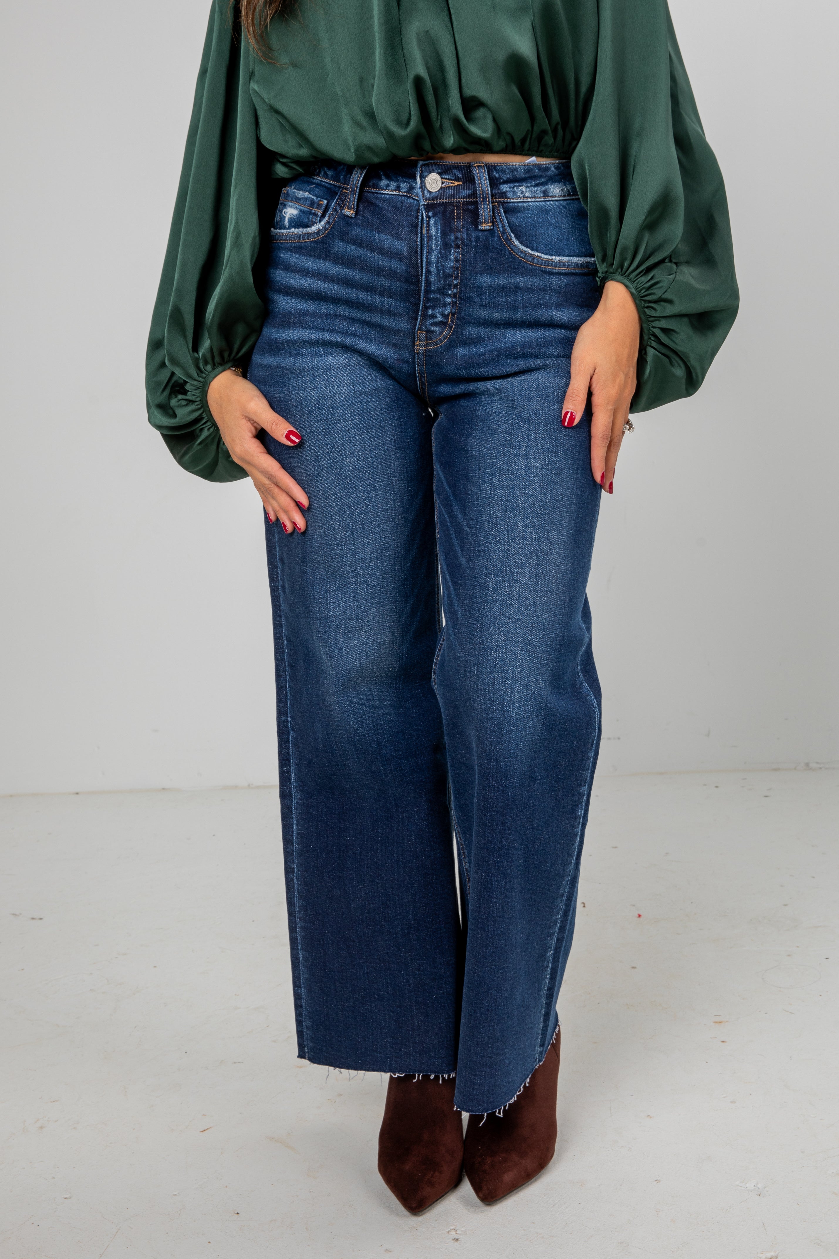 Person wearing blue jeans and a green top on a white background