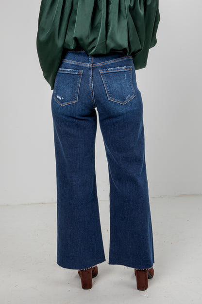 Person wearing blue jeans and a green top on a white background
