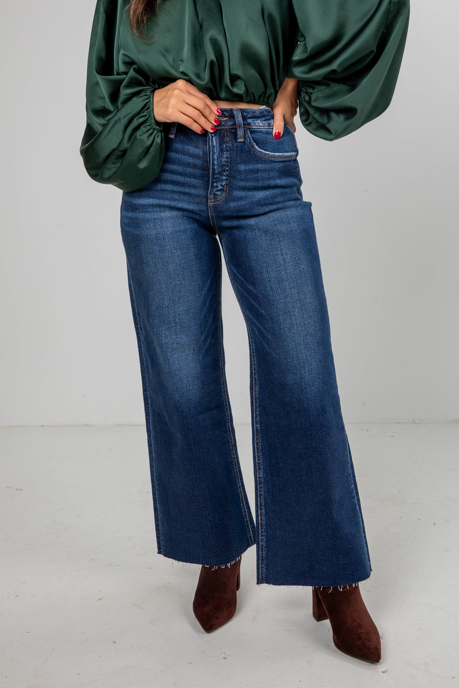 Person wearing a green blouse and blue jeans on a white background