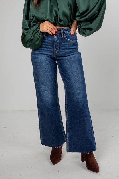 Person wearing a green blouse and blue jeans on a white background