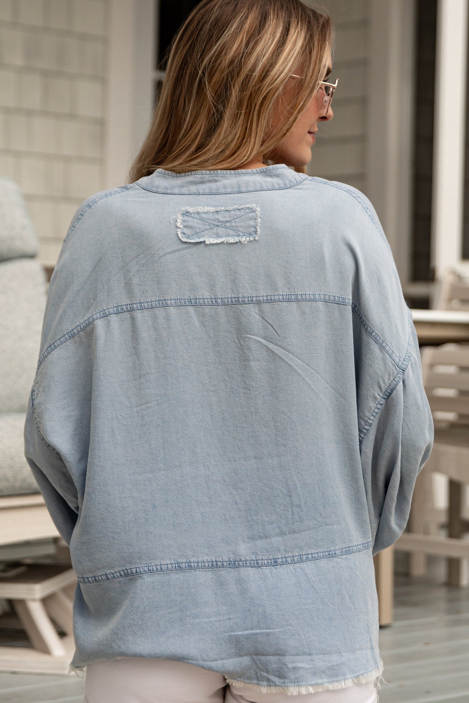 Woman wearing a light blue denim jacket on a patio