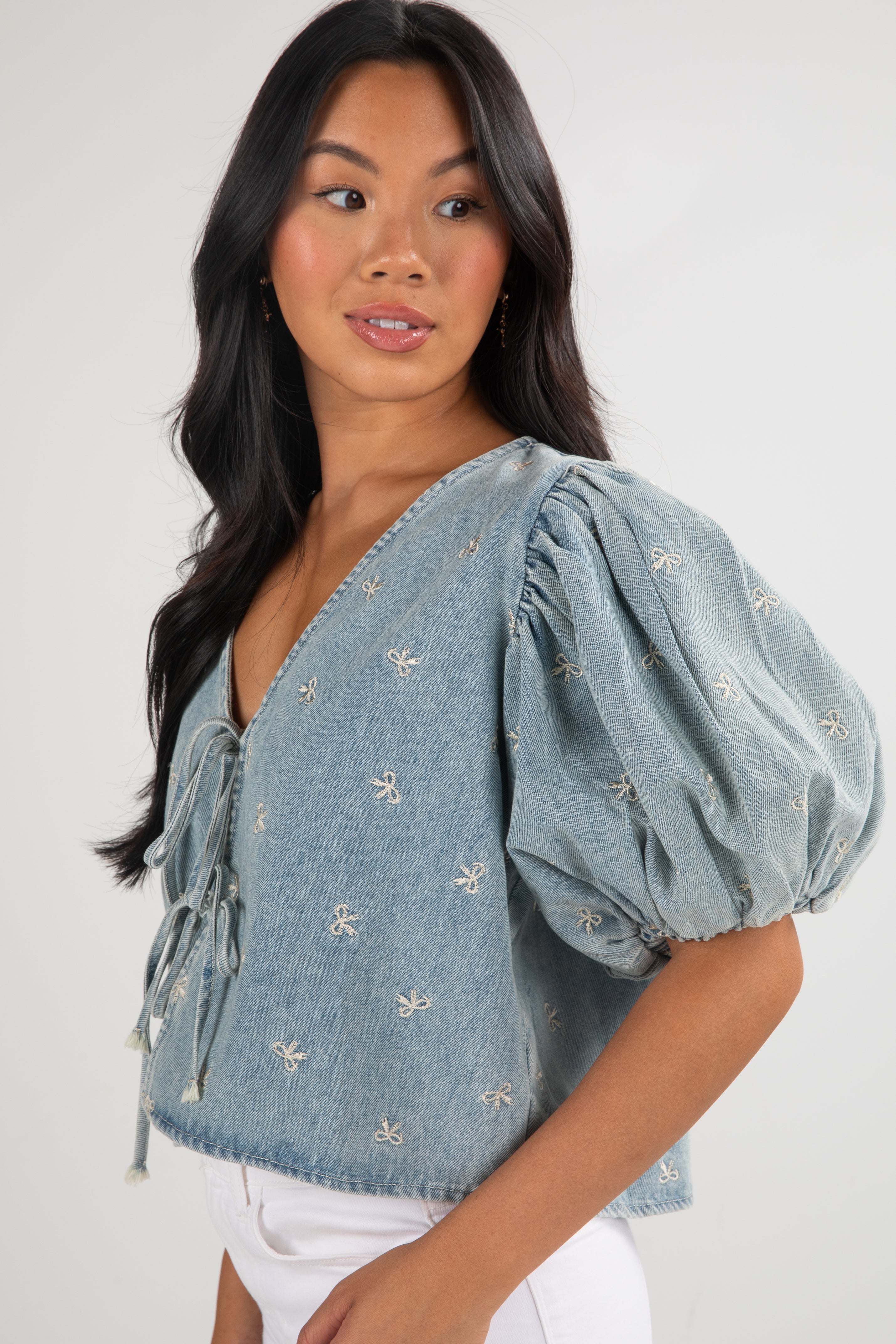 Woman wearing a blue denim blouse with puff sleeves on a white background