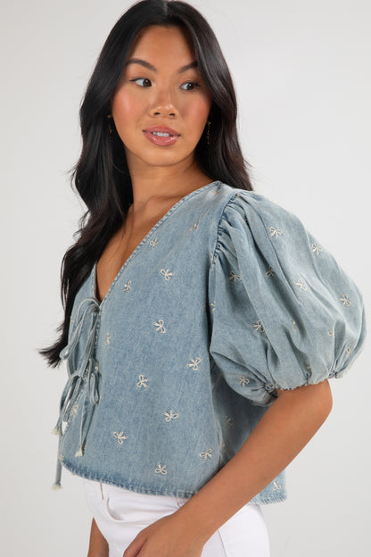 Woman wearing a blue denim blouse with puff sleeves on a white background