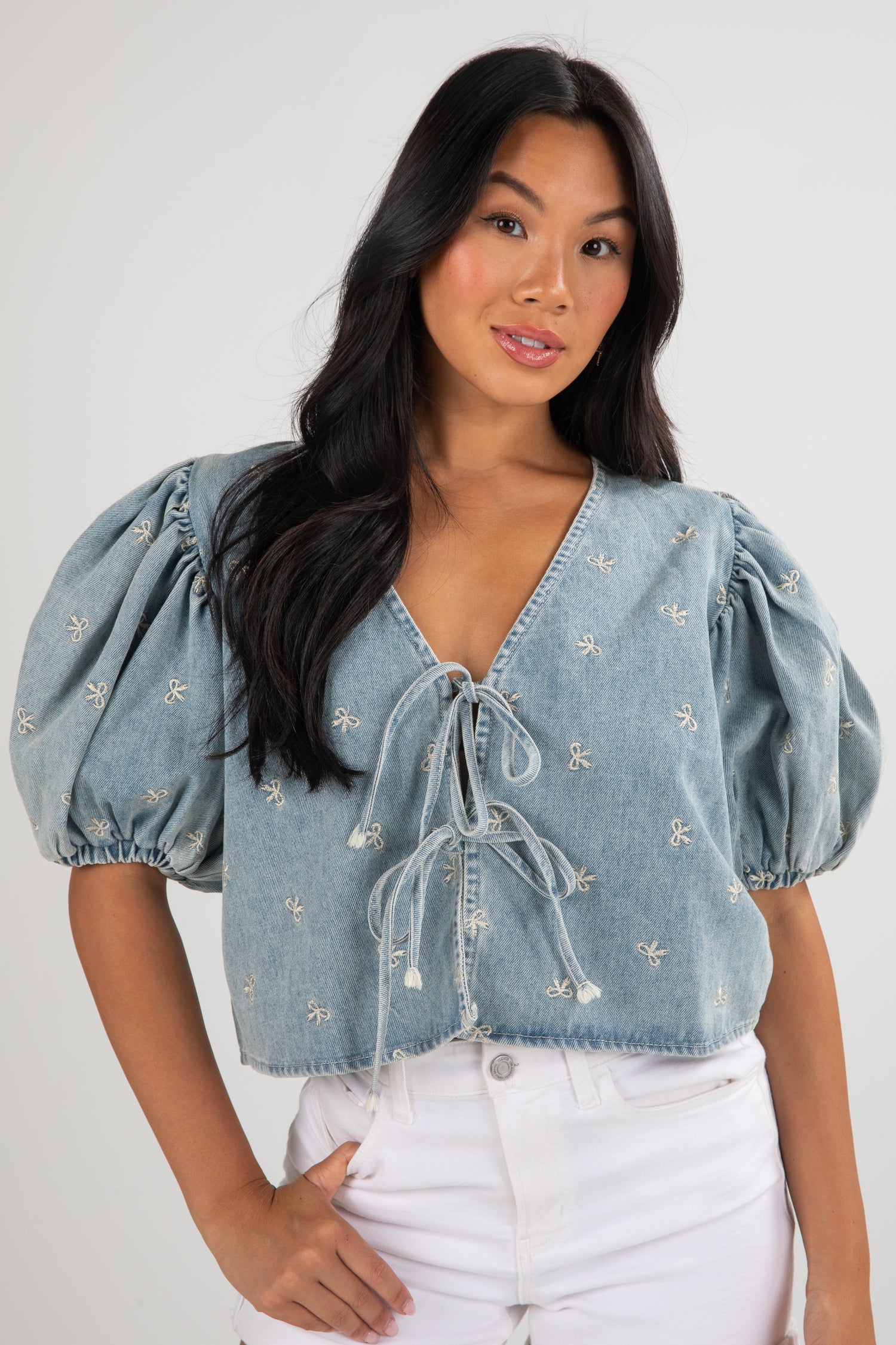 Woman wearing a light blue denim top with puff sleeves against a white background