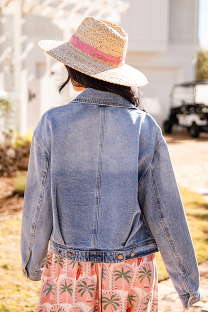 Person wearing a denim jacket and straw hat with a blurred background
