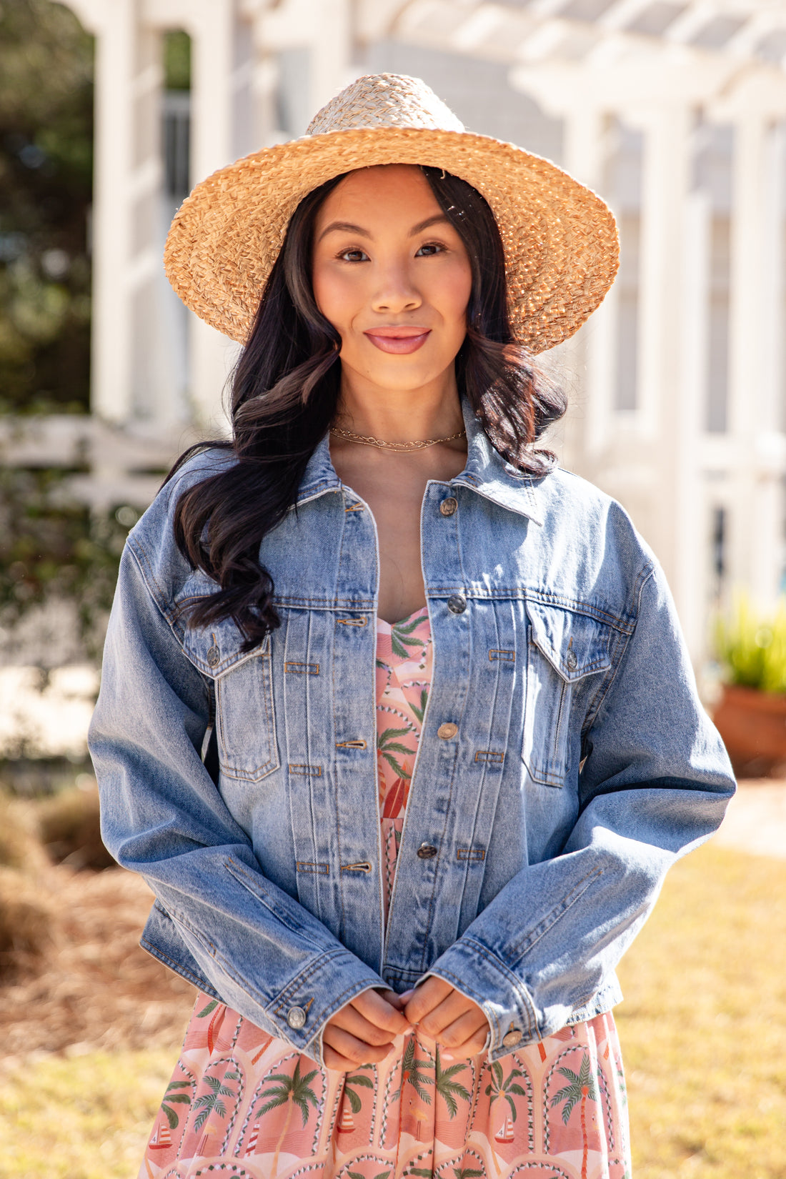 Woman wearing a denim jacket and straw hat outdoors