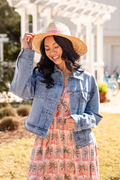 Woman wearing a straw hat and denim jacket outdoors