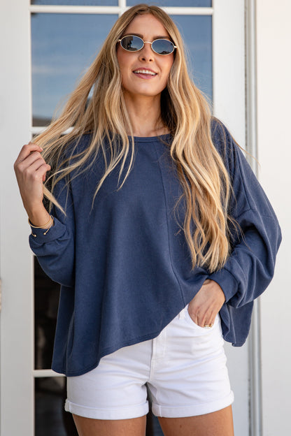 Woman wearing a blue top and white shorts standing in front of a glass door.