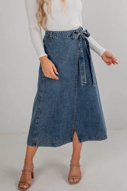 Person wearing a blue denim skirt on a plain background