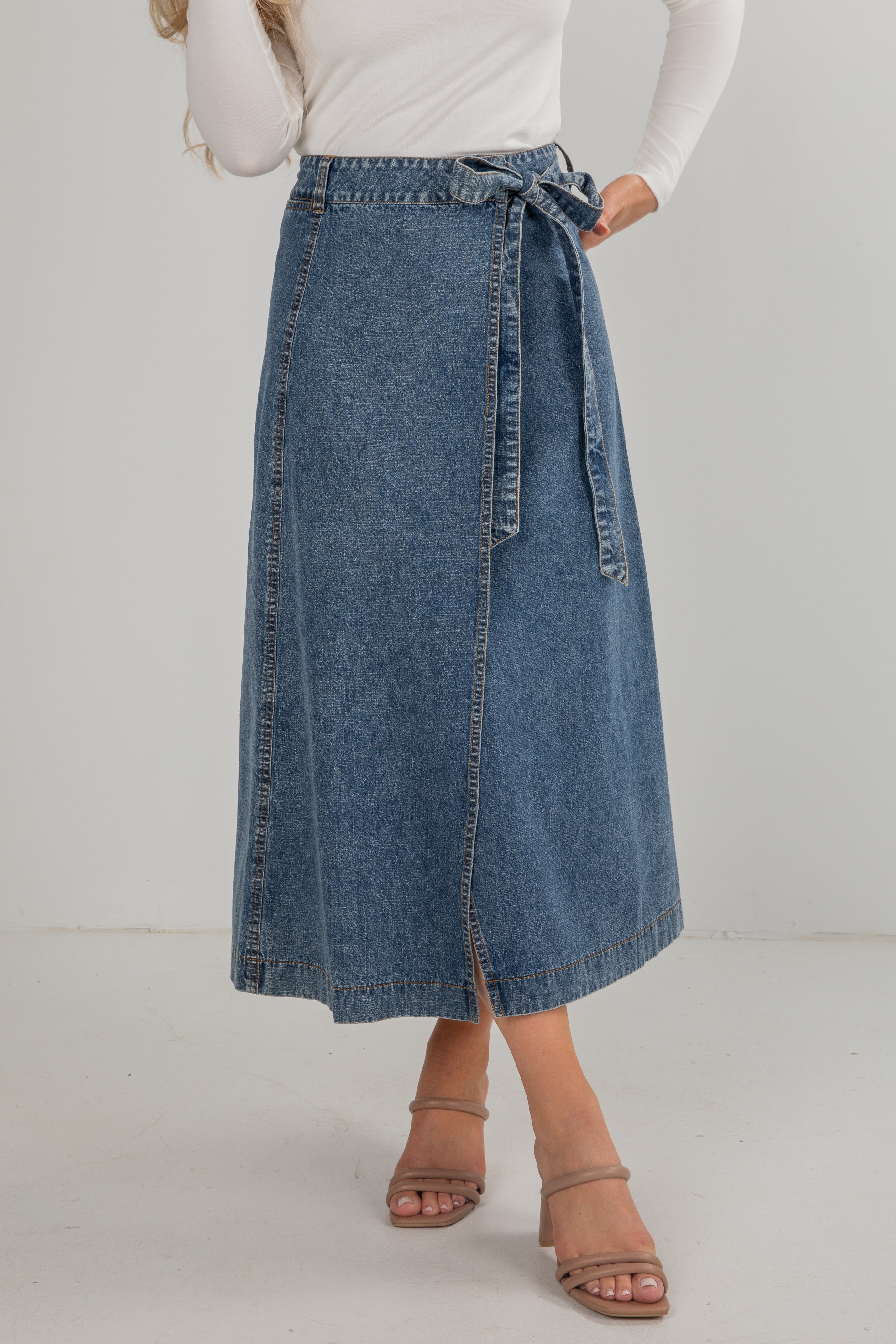 Person wearing a blue denim skirt on a white background
