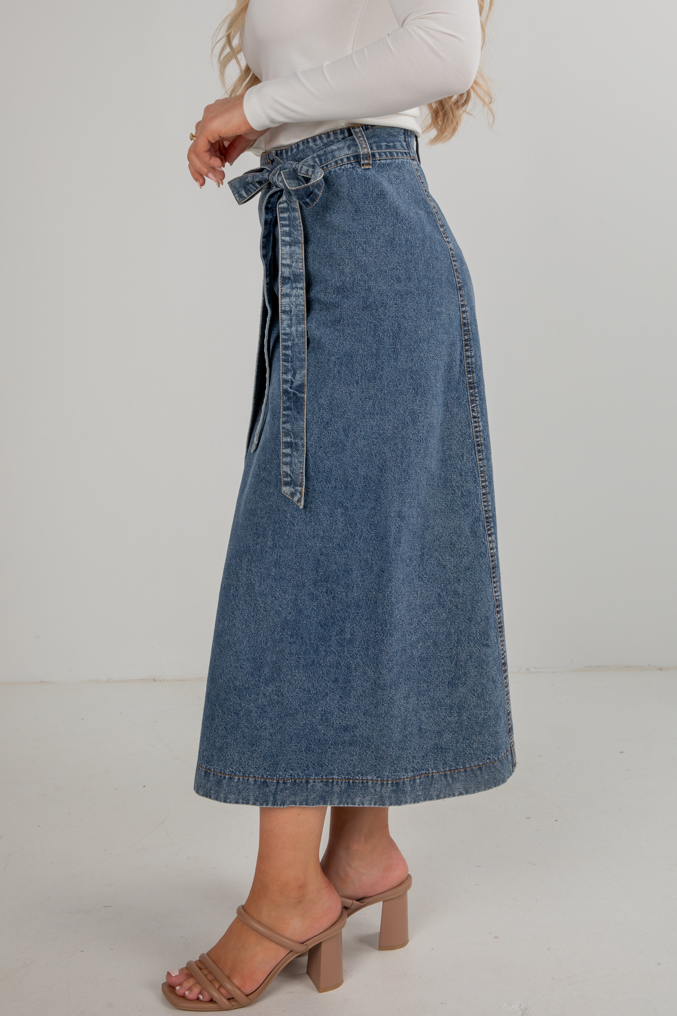 Person wearing a blue denim skirt on a plain background