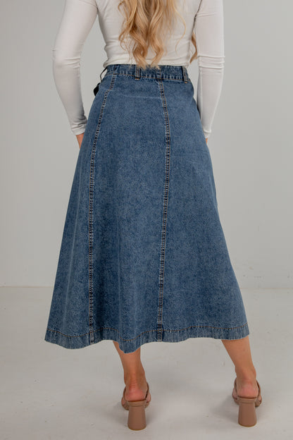 Person wearing a blue denim skirt on a plain background