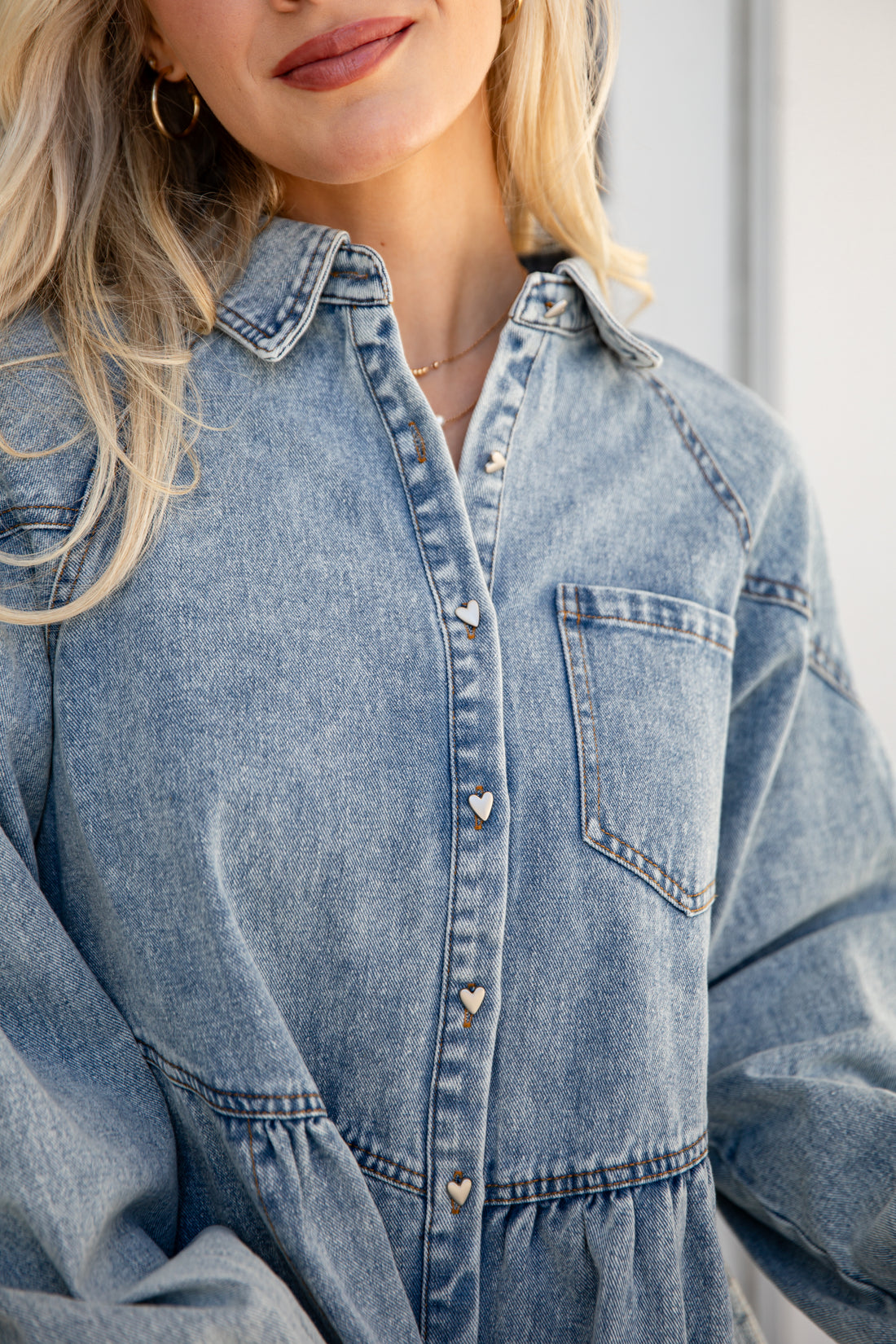 Person wearing a light blue denim dress with a neutral background