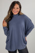 Woman wearing a blue turtleneck sweater against a gray background