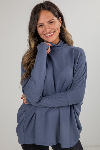 Woman wearing a blue turtleneck sweater against a white background