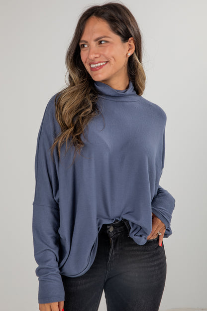 Woman wearing a blue long-sleeve top against a plain background