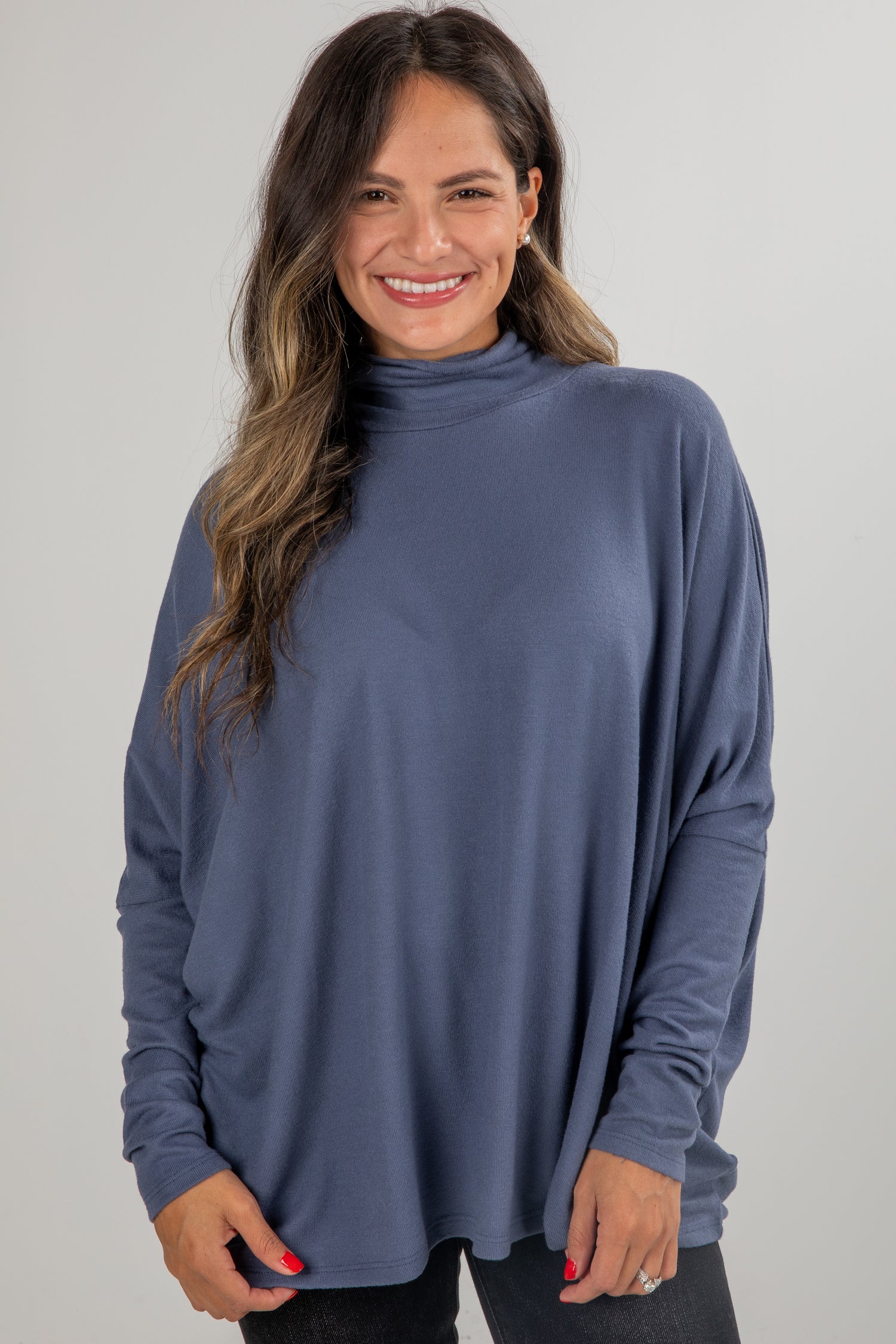 Woman wearing a blue long-sleeve top against a gray background