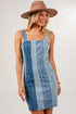 A woman wearing a light blue denim patchwork mini dress with wide shoulder straps and a matching brown wide-brim fedora hat, posing against a plain white studio background.