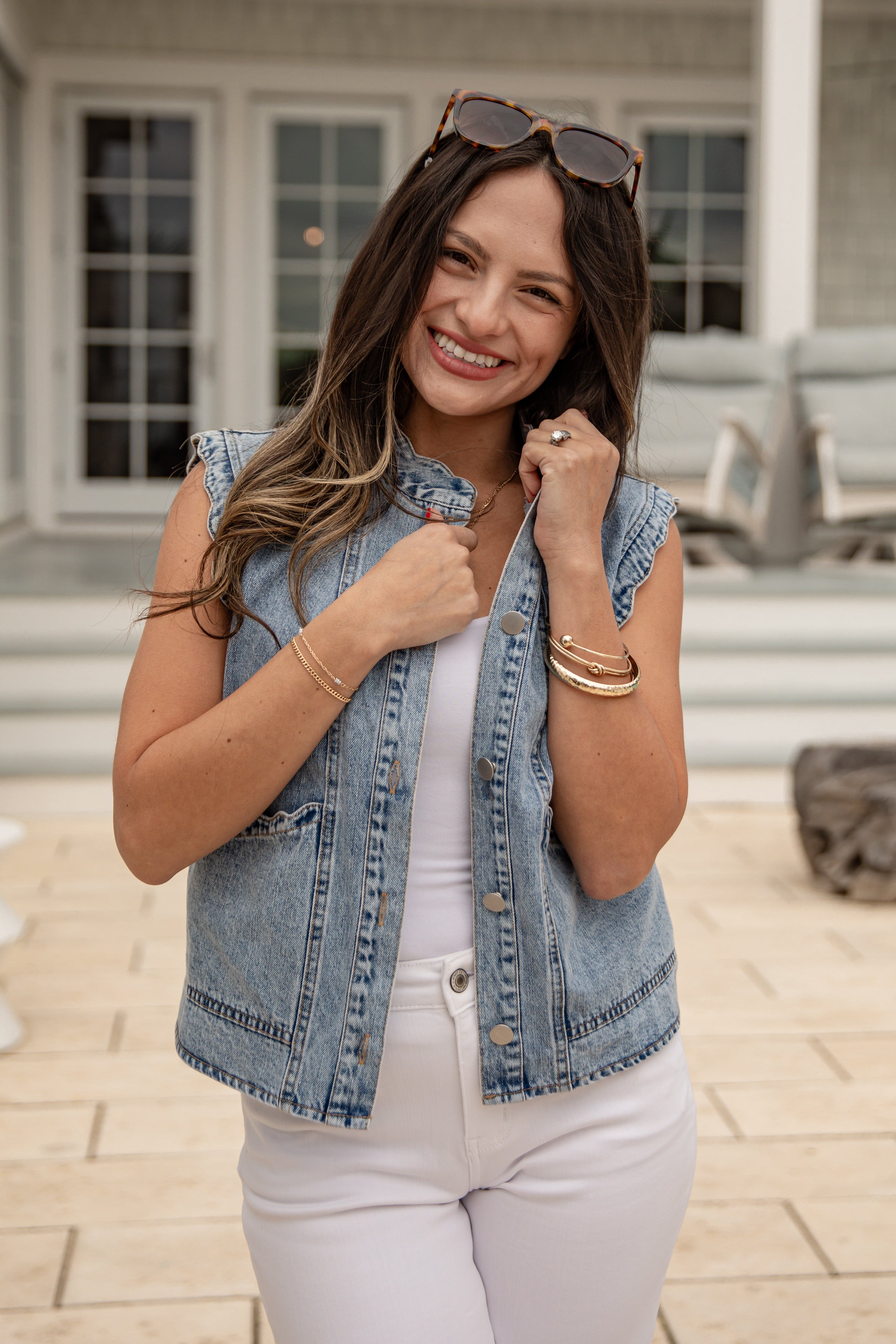 Woman wearing a denim vest and white pants outdoors.