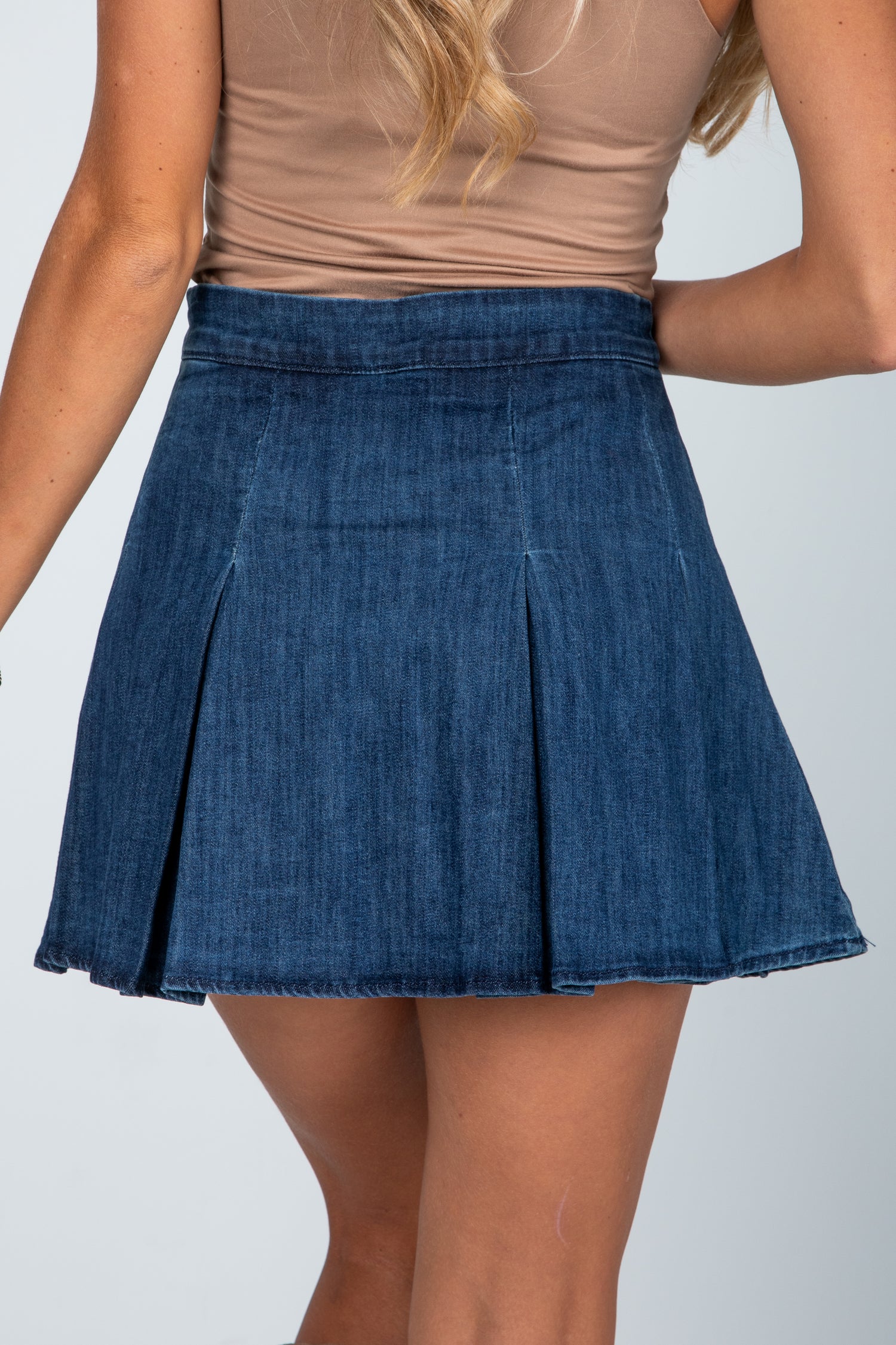 Person wearing a blue denim skirt on a plain background