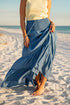 Person wearing a blue skirt on a sandy beach with ocean view
