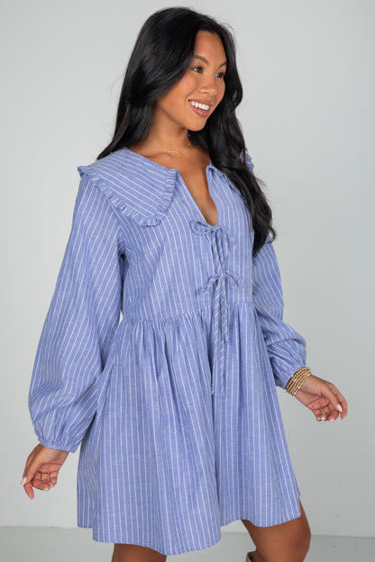 Woman wearing a blue striped dress against a plain background