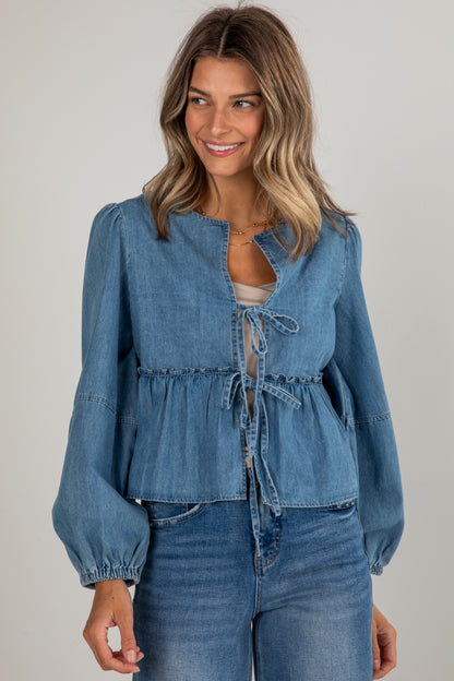 Woman wearing a blue denim top and jeans on a gray background