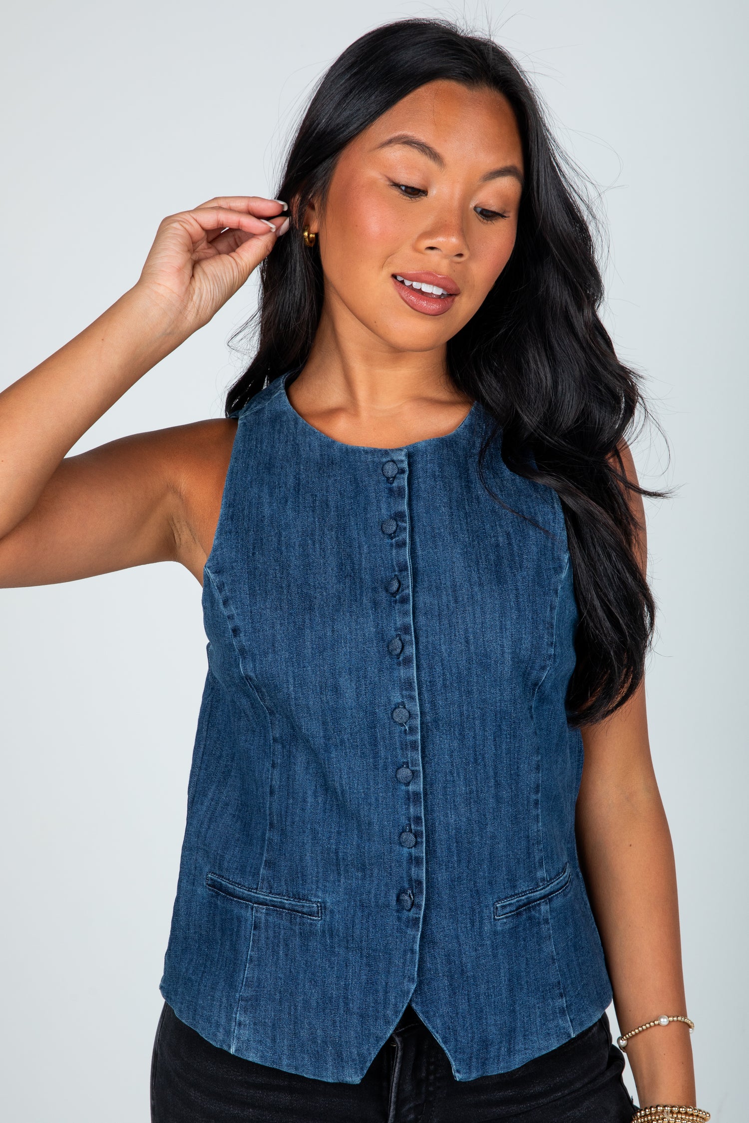 Woman wearing a blue denim vest against a plain background