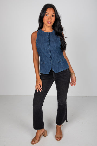 Woman wearing a denim vest and black pants on a white background