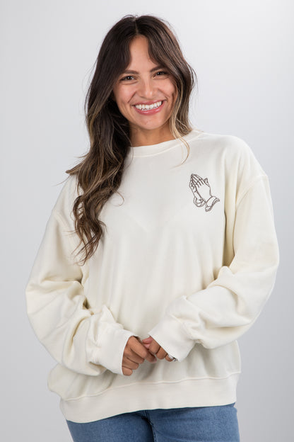 Woman wearing a cream-colored sweatshirt with a small design on a plain background