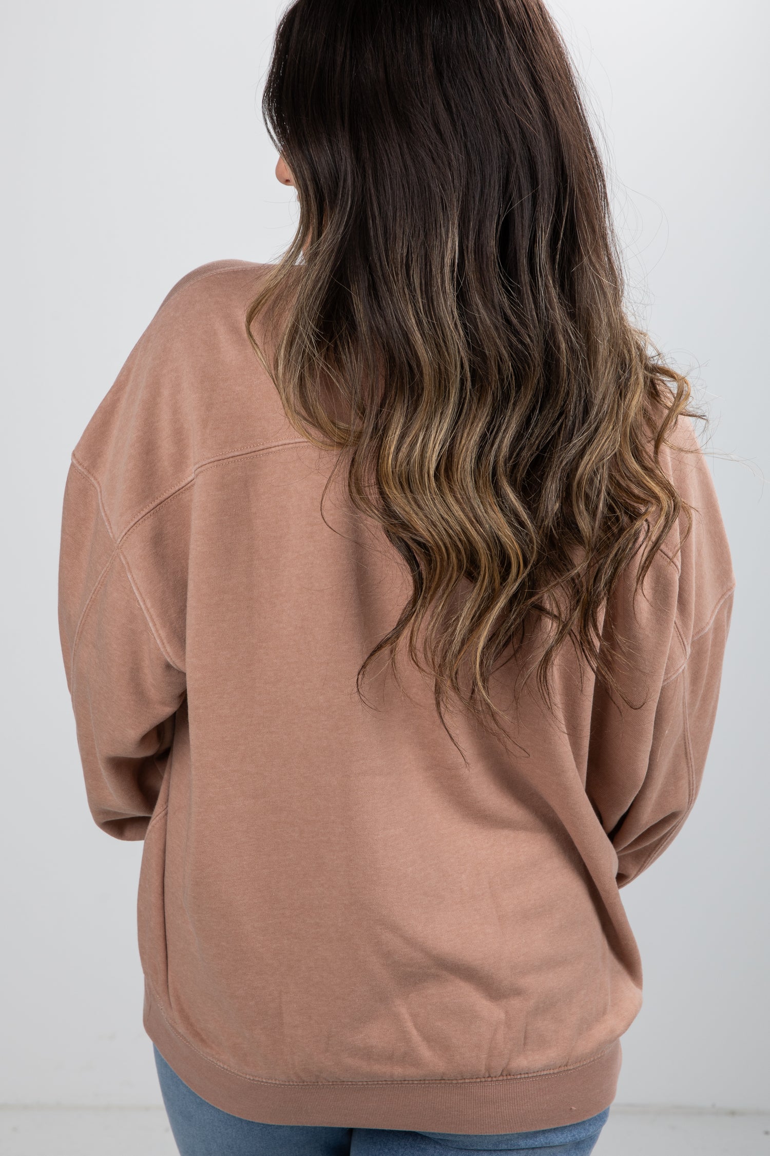 Person wearing a brown sweatshirt with a plain white background