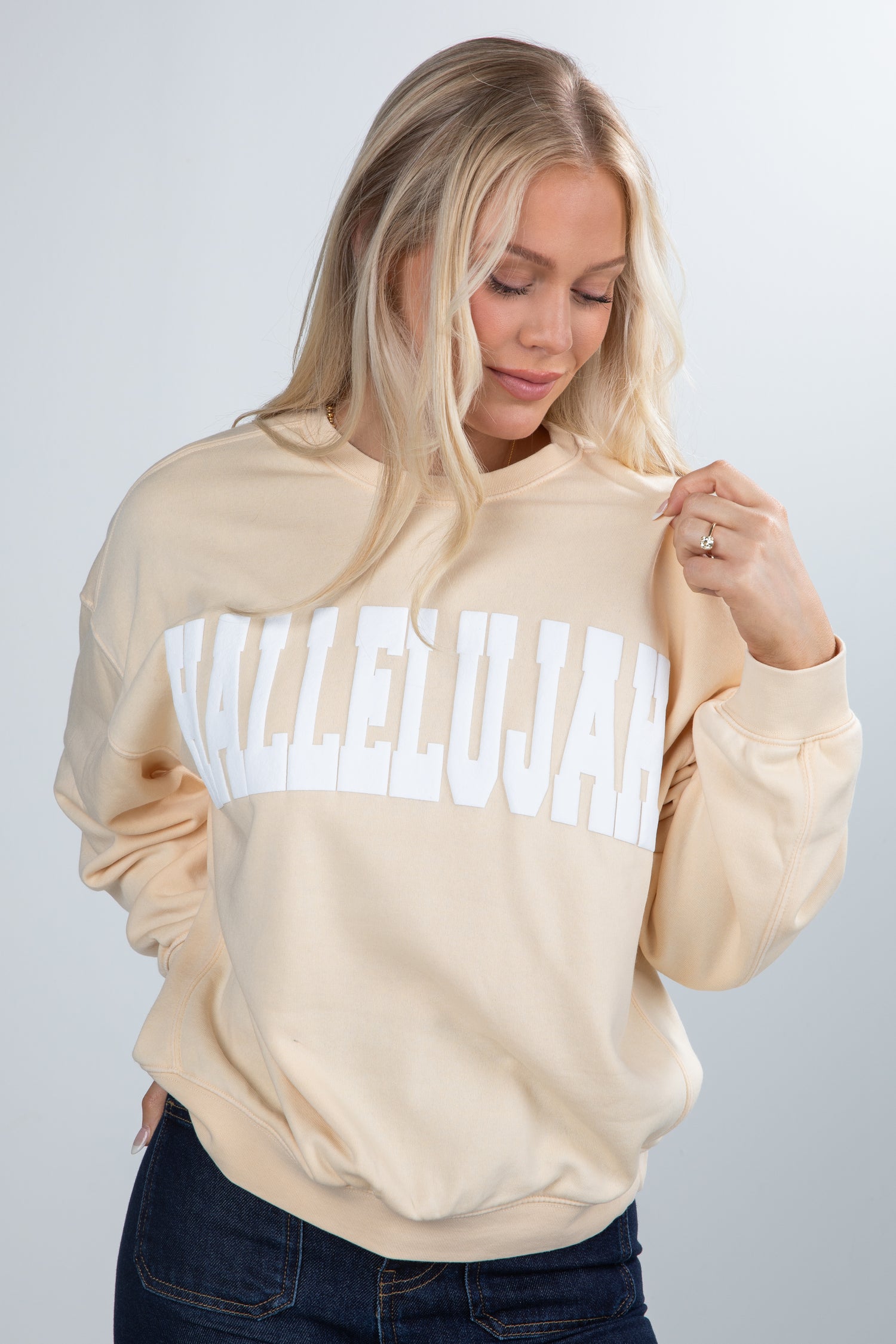 Woman wearing a beige sweatshirt with &