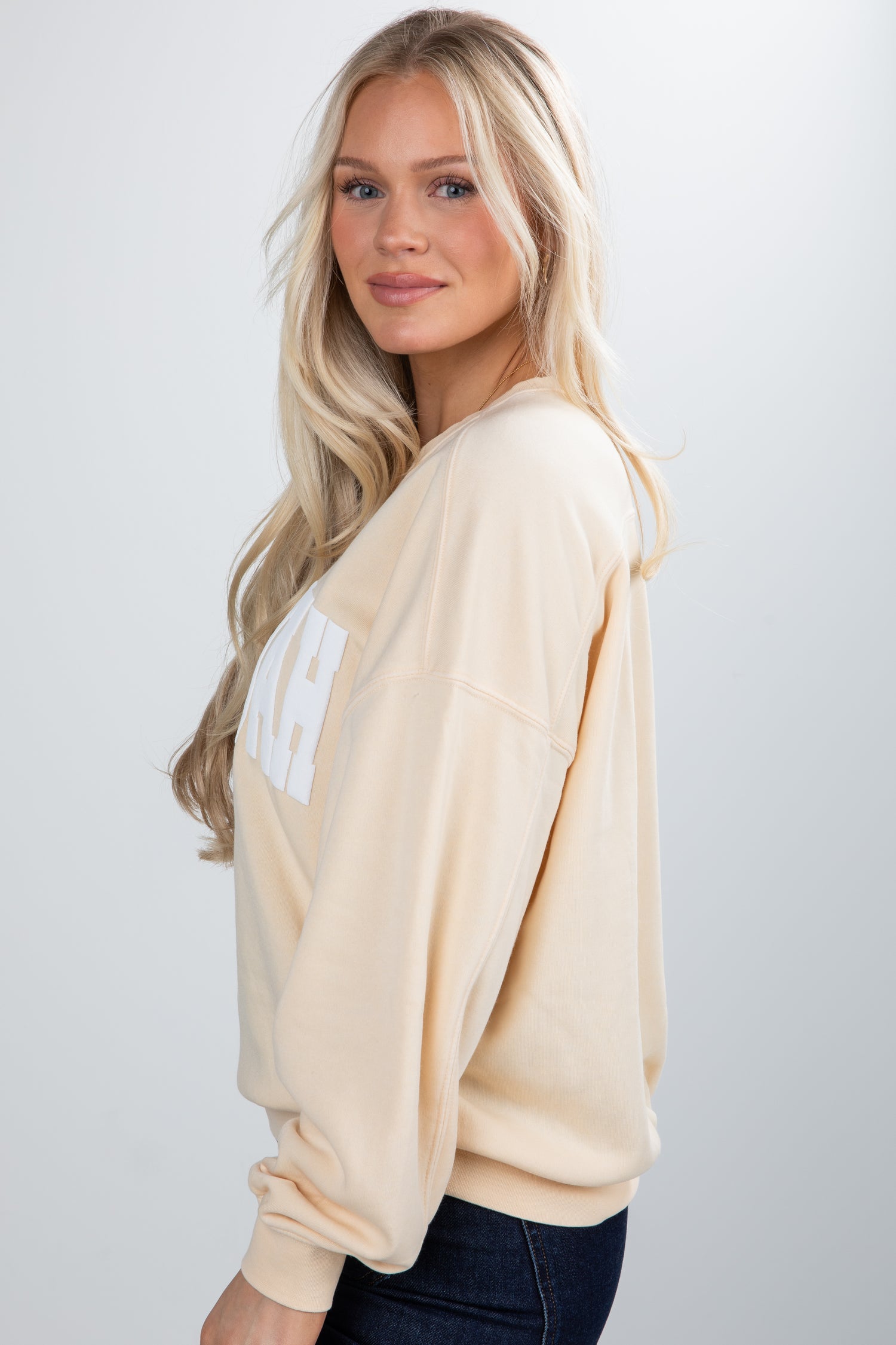 Woman wearing a beige sweater with a logo on a white background