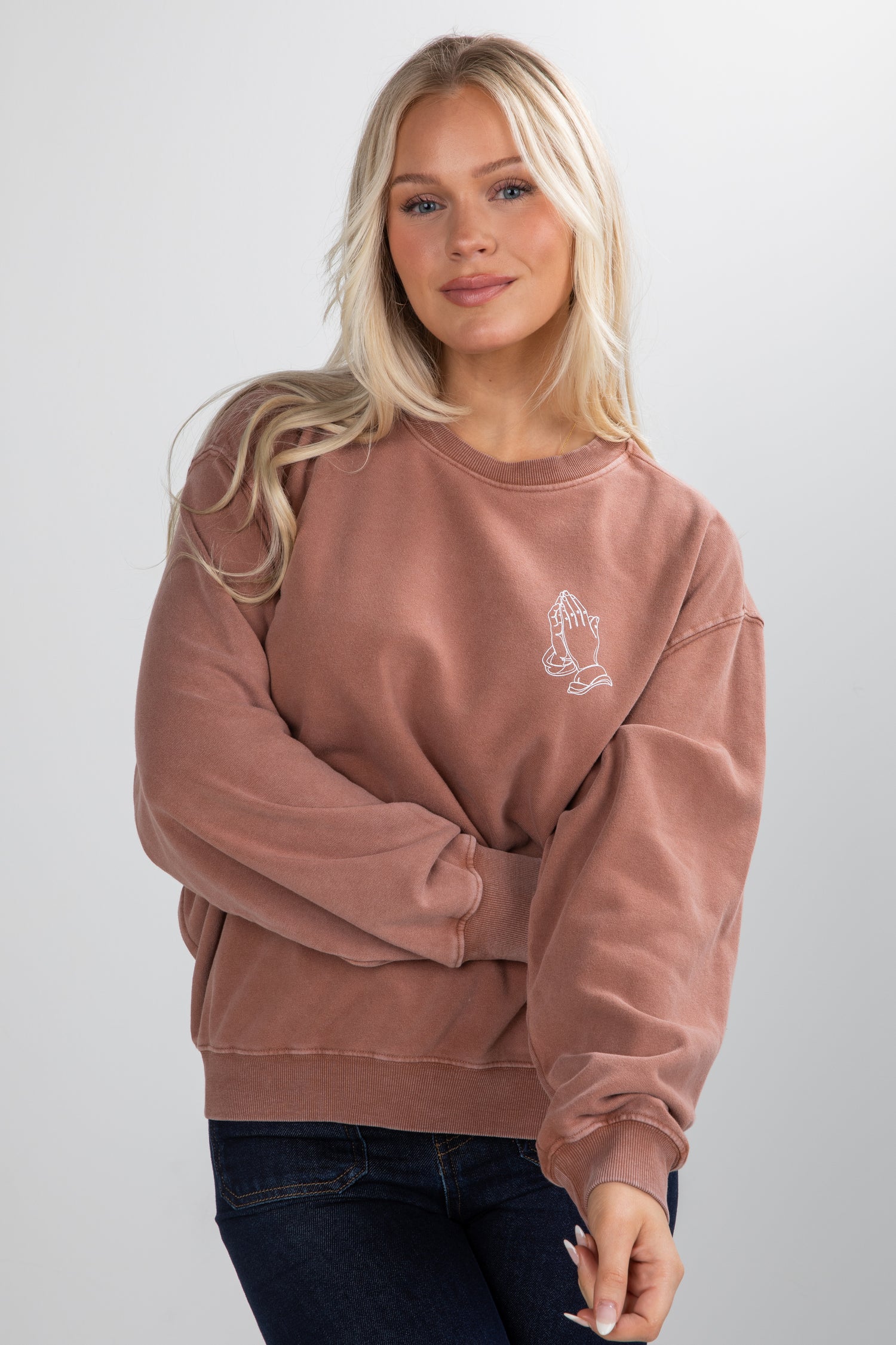 Woman wearing a pink sweatshirt with a small graphic on a white background