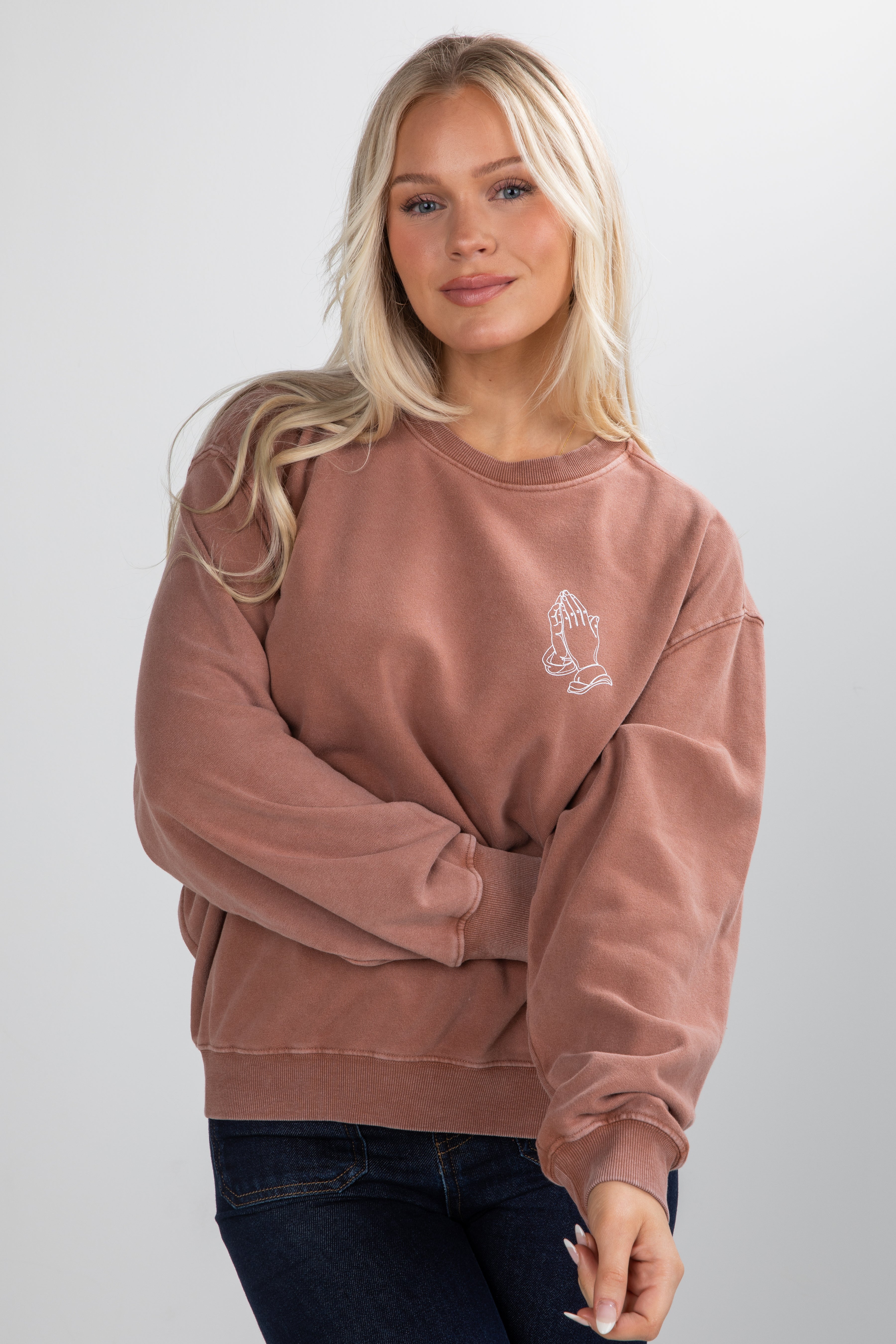 Woman wearing a pink sweatshirt with a small graphic on a white background